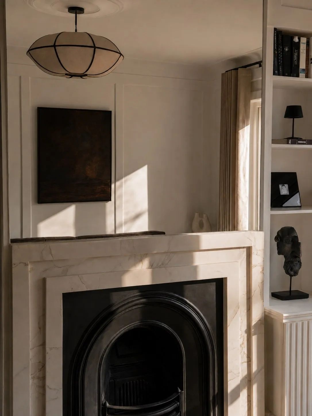 Custom fireplace with marble surround, cast iron insert and bespoke shelving in a panelled family living room