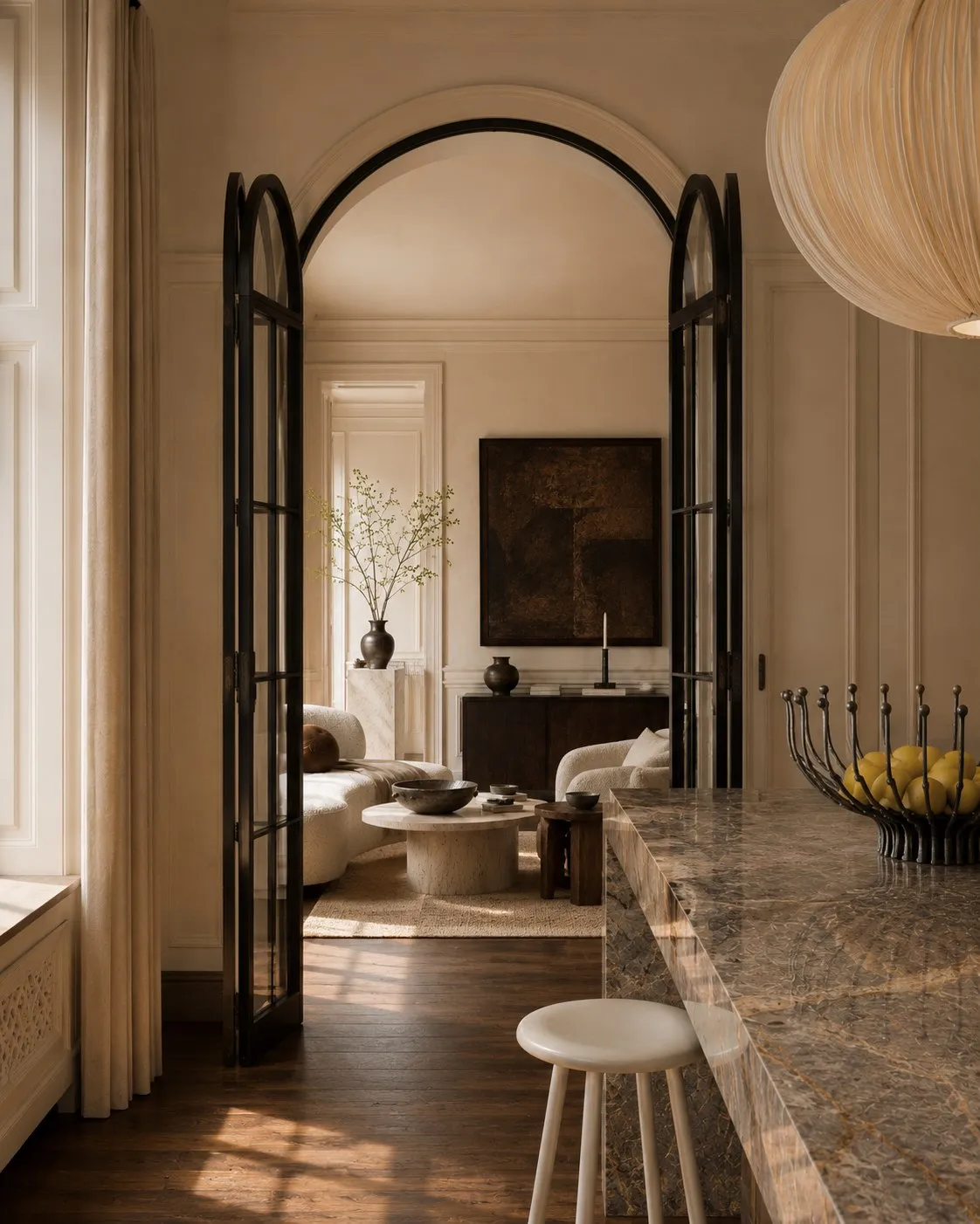Monolithic stone island seen through arched Crittall-style doors into the living room