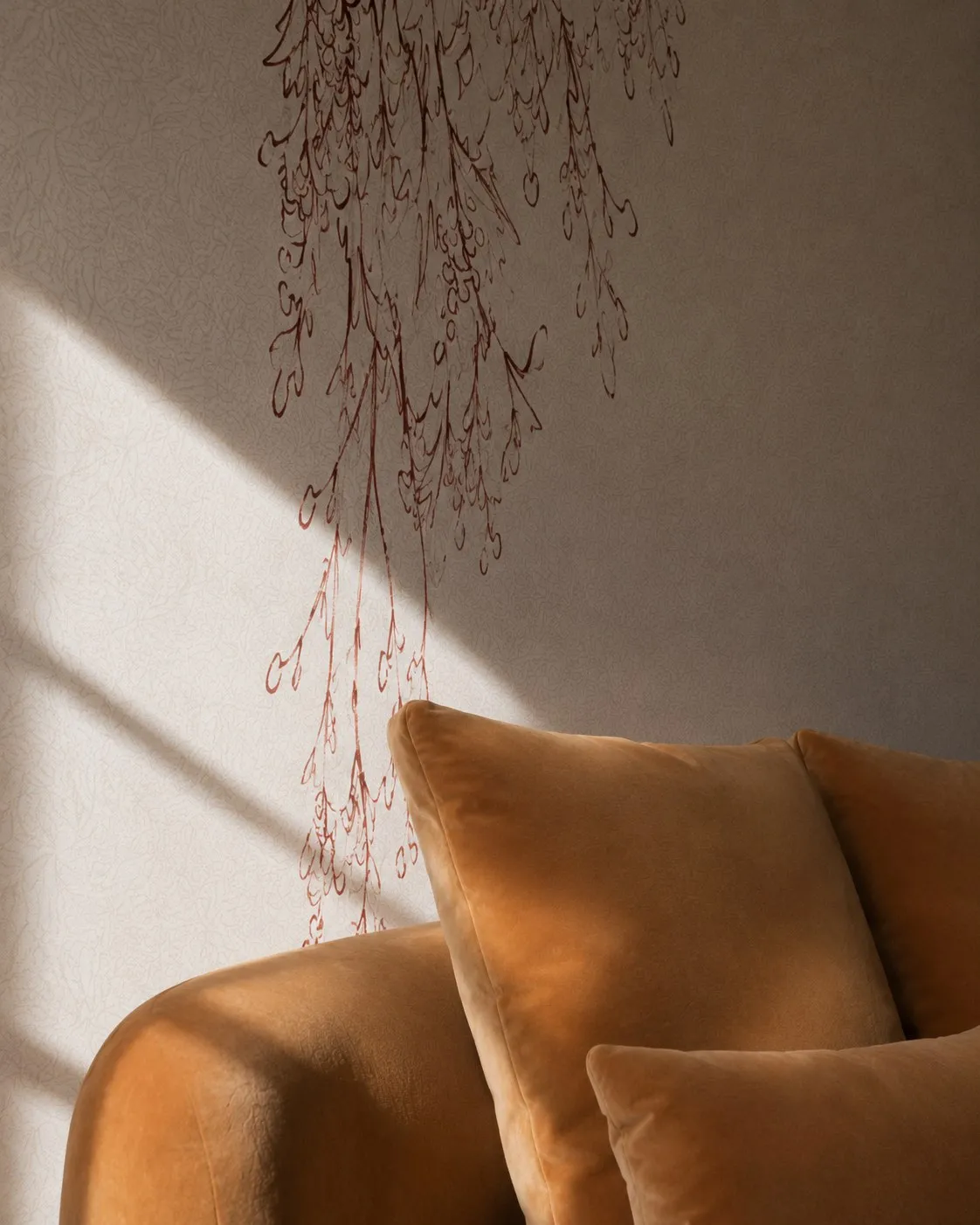 Cascading branch wallpaper detail falling behind the curved gold velvet sofa