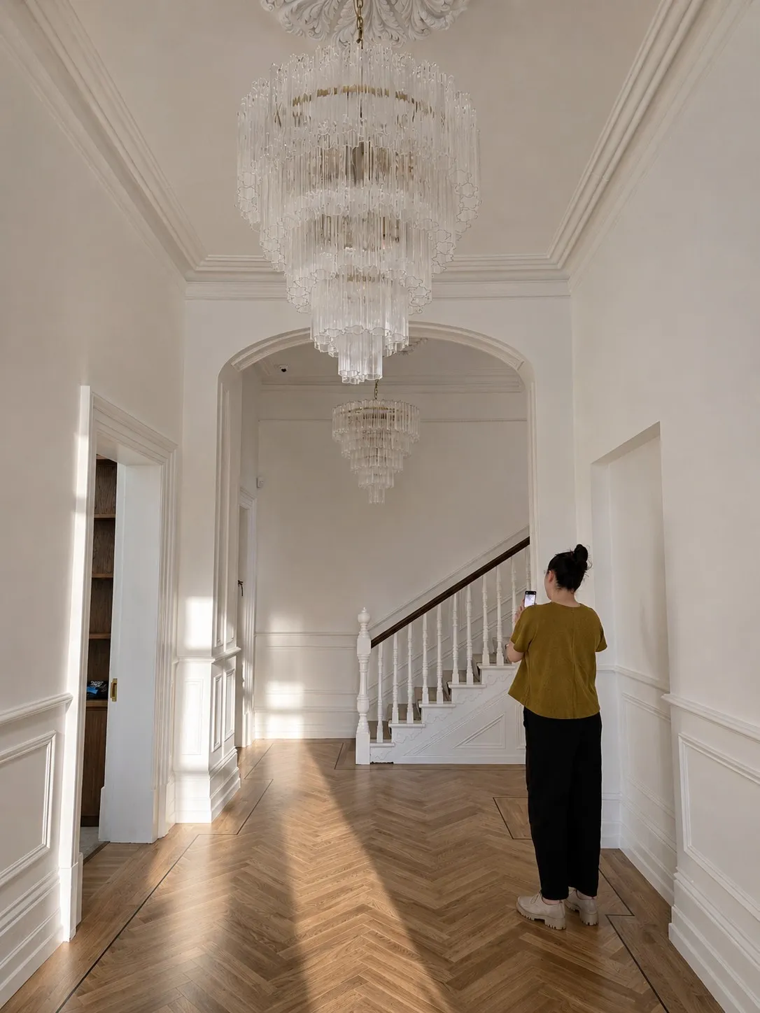 Restored hallway with lime plaster walls in raking sunlight, herringbone oak floor and panelled dado