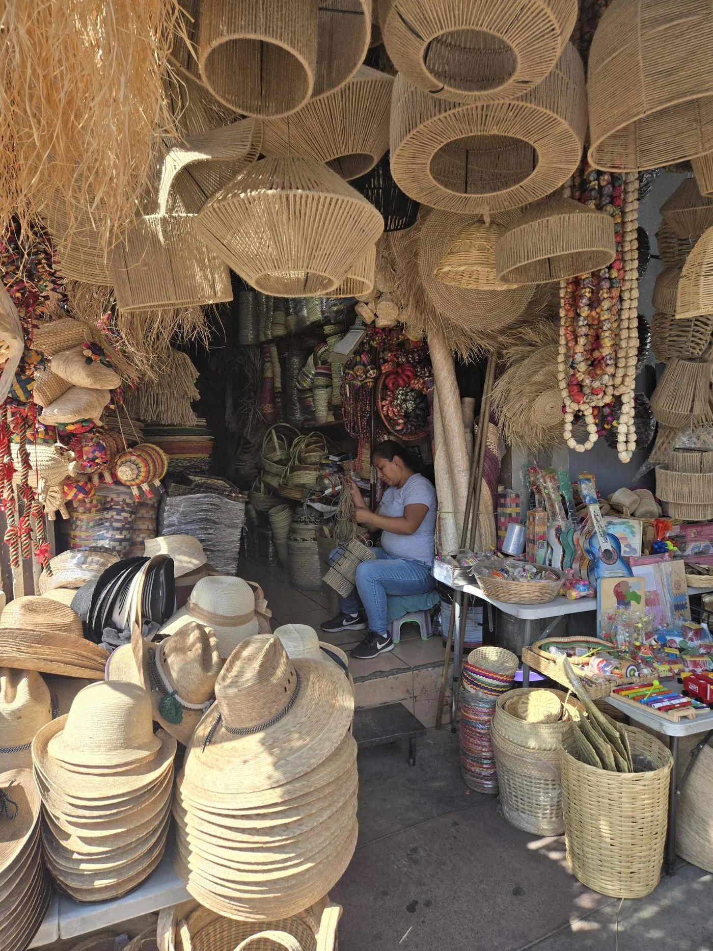 A maker weaving palm fibre baskets and hats in a market stall in Mexico
