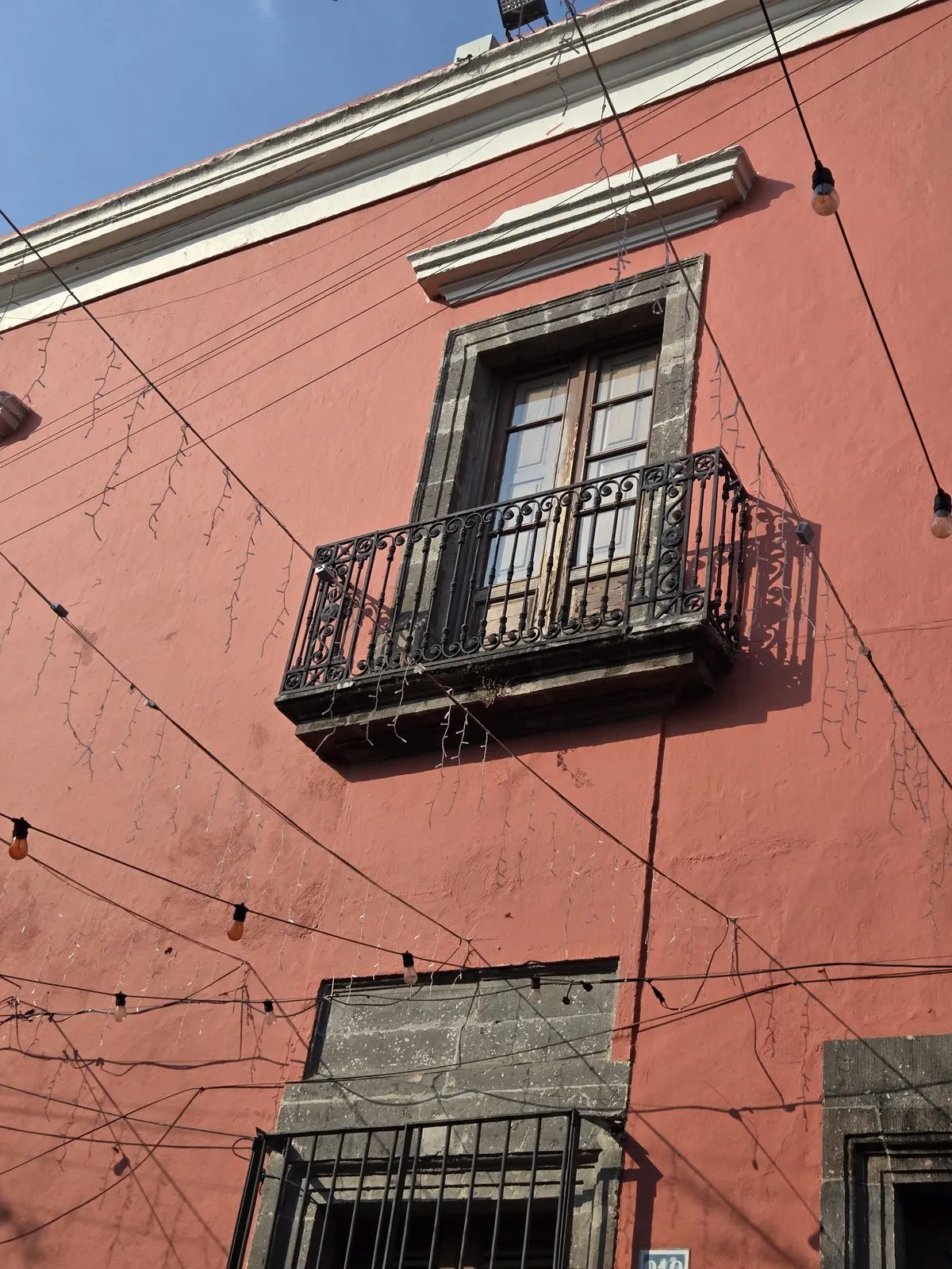 Traditional Mexican building facade with deep window reveals and wrought iron balcony