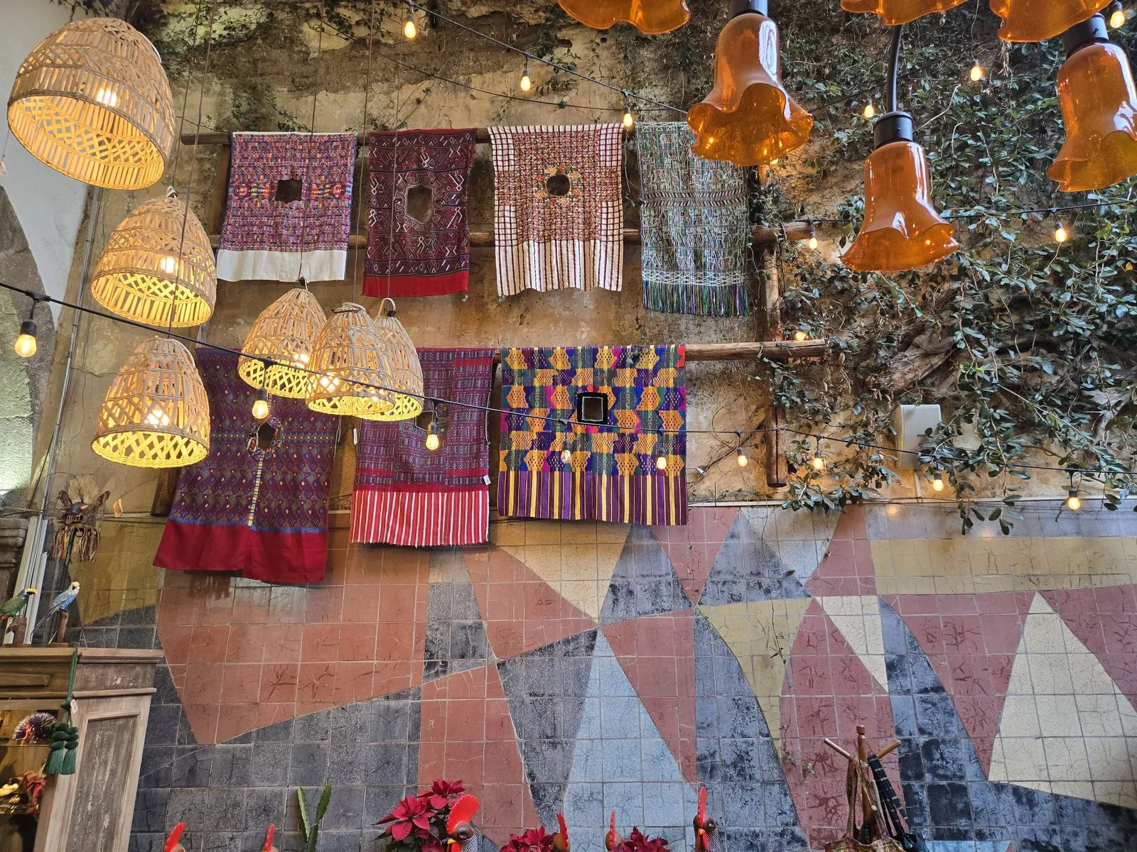 Handwoven Mexican textiles displayed on a wall alongside woven rattan lighting