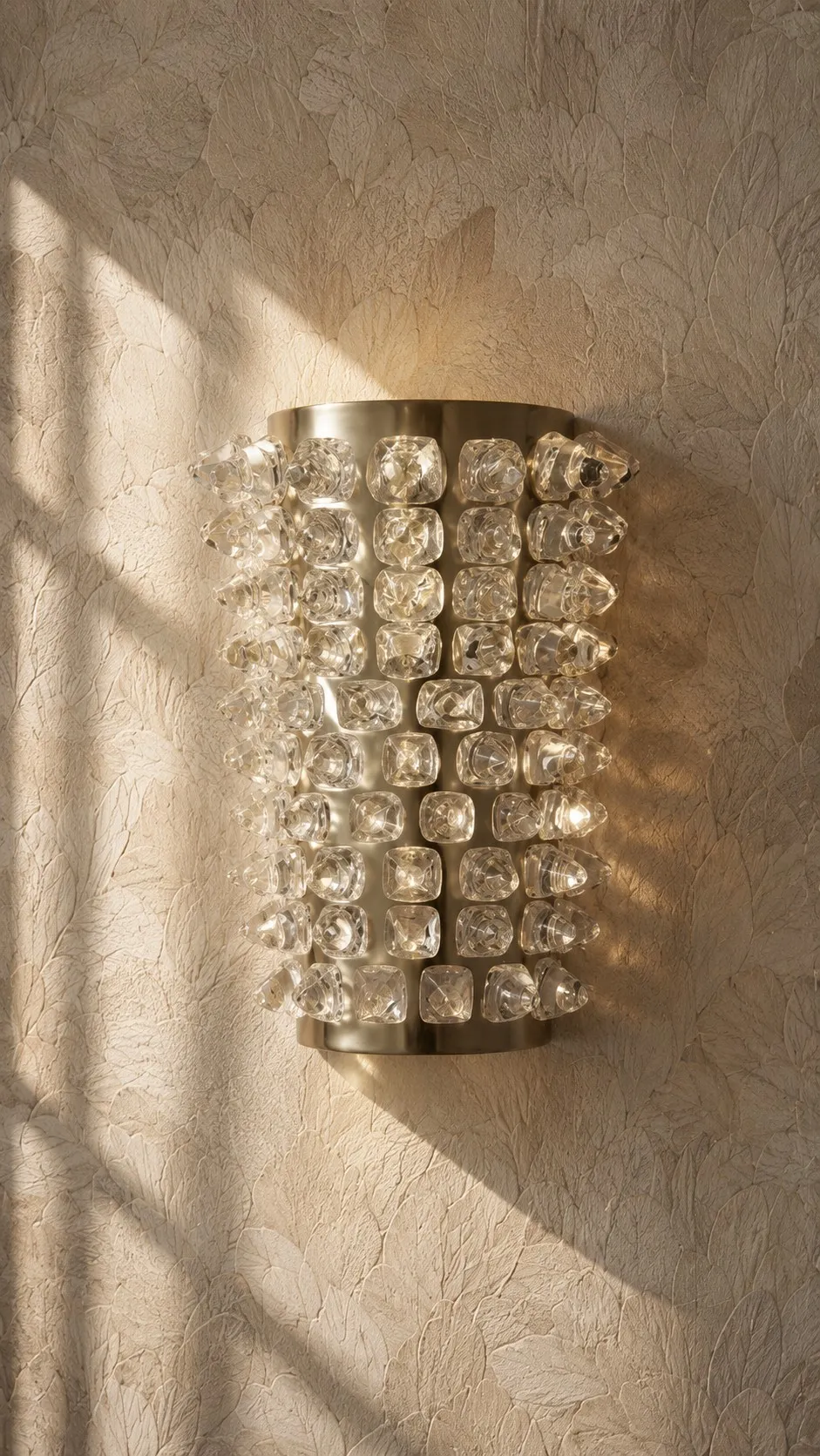 Detail of a crystal wall sconce against leaf-textured plaster
