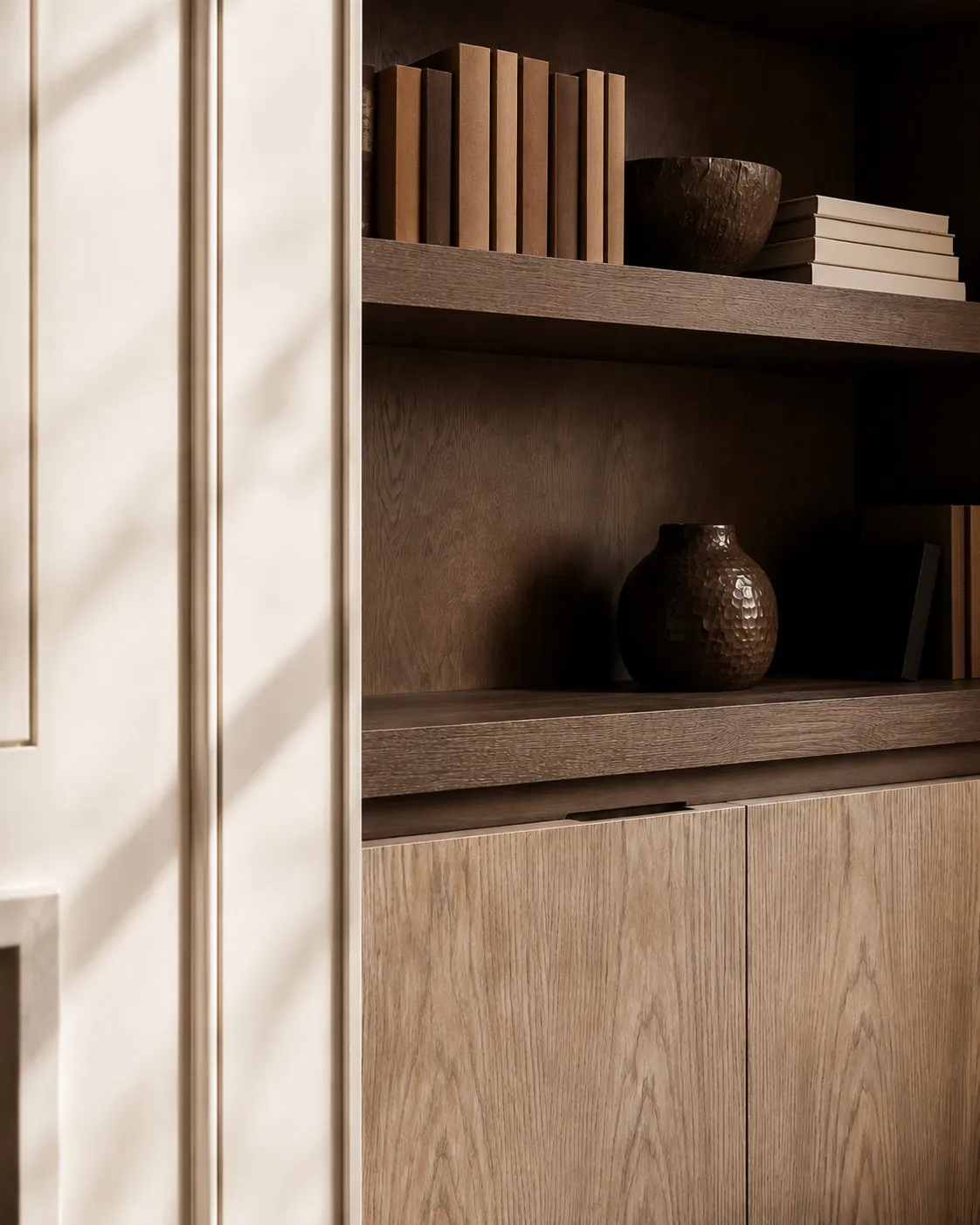 Detail of dark timber shelving with books and collected ceramics